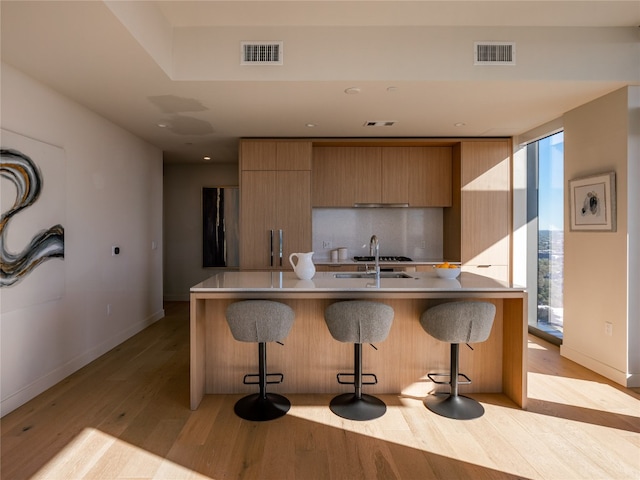 kitchen with light countertops, visible vents, a center island with sink, and modern cabinets