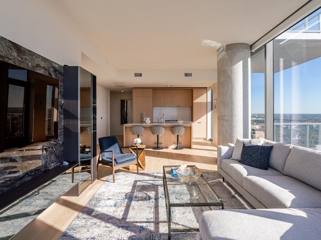 living area featuring light wood-type flooring, visible vents, and floor to ceiling windows