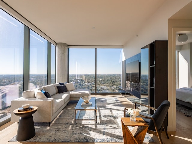 living room featuring hardwood / wood-style flooring, a healthy amount of sunlight, and a wall of windows