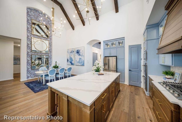 kitchen with beamed ceiling, a center island, appliances with stainless steel finishes, and high vaulted ceiling