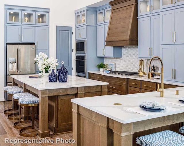 kitchen with a large island, custom exhaust hood, dark wood-type flooring, and appliances with stainless steel finishes