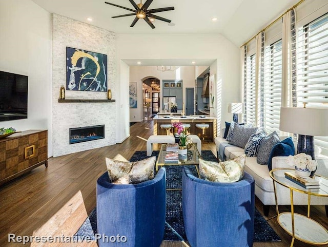 living room with a fireplace, dark hardwood / wood-style floors, ceiling fan, and lofted ceiling