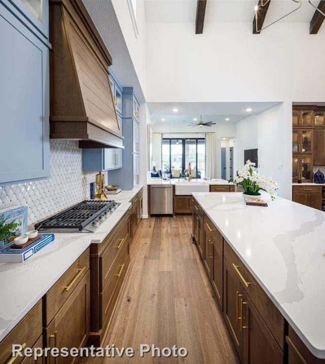 kitchen with ceiling fan, stainless steel appliances, tasteful backsplash, light hardwood / wood-style flooring, and custom exhaust hood