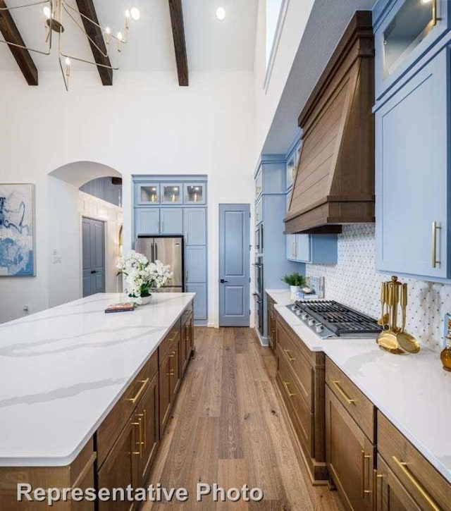 kitchen with beam ceiling, a center island, dark hardwood / wood-style floors, decorative backsplash, and appliances with stainless steel finishes