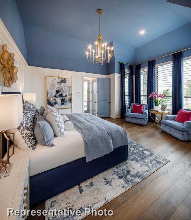 bedroom featuring hardwood / wood-style flooring, a chandelier, and vaulted ceiling