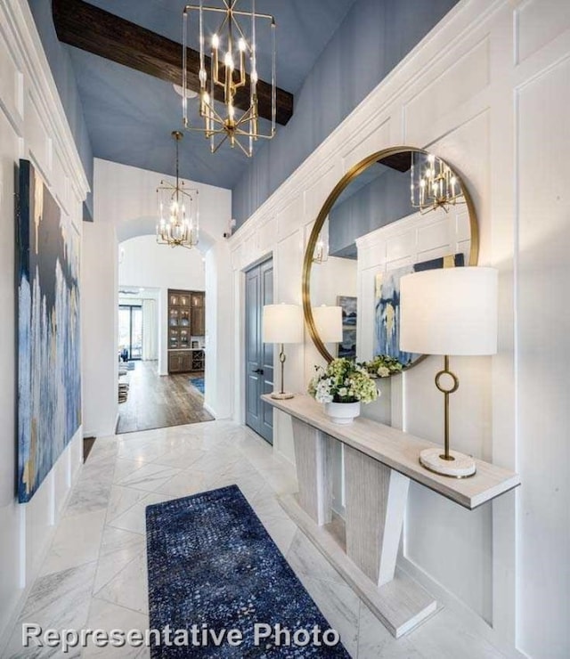 hallway featuring beamed ceiling, a towering ceiling, and light hardwood / wood-style floors