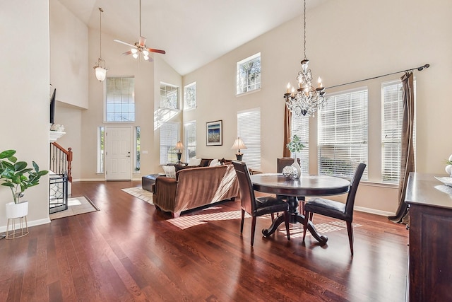 dining space featuring ceiling fan with notable chandelier, a high ceiling, and dark hardwood / wood-style flooring