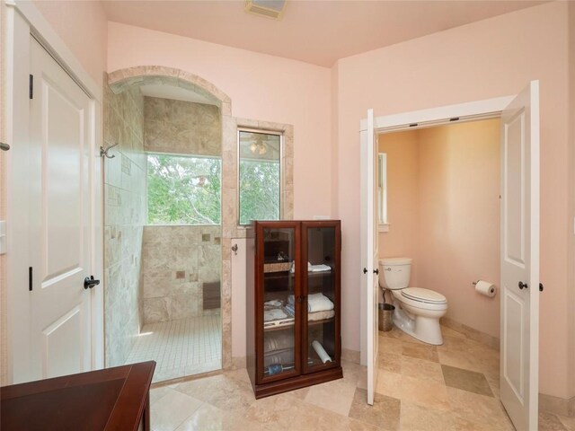 bathroom with tiled shower and toilet