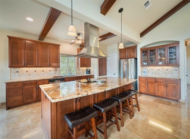 kitchen with light stone countertops, appliances with stainless steel finishes, island range hood, and a kitchen breakfast bar