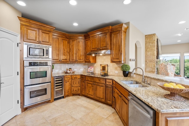 kitchen with kitchen peninsula, light stone counters, stainless steel appliances, sink, and wine cooler