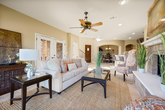 living room featuring french doors and ceiling fan with notable chandelier