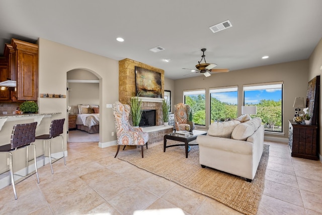 living room featuring a fireplace, light tile patterned floors, and ceiling fan