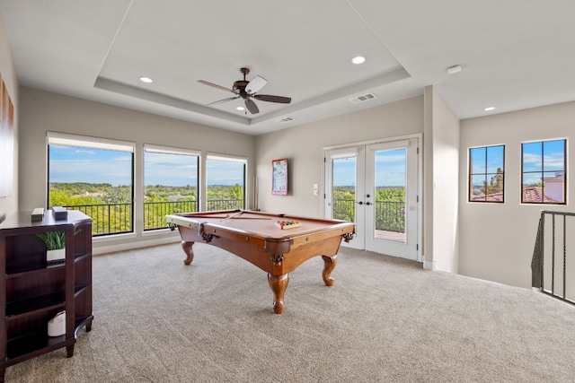 game room with ceiling fan, a raised ceiling, light colored carpet, and french doors