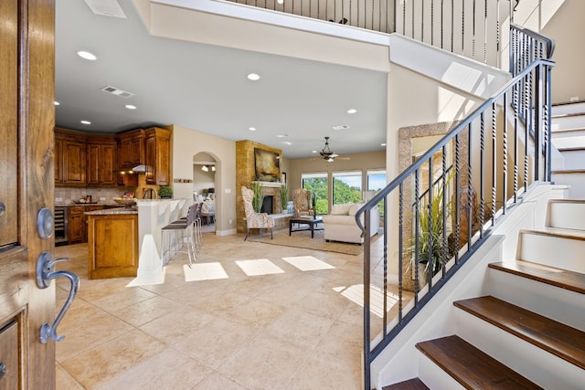 foyer featuring ceiling fan, light tile patterned flooring, and a fireplace