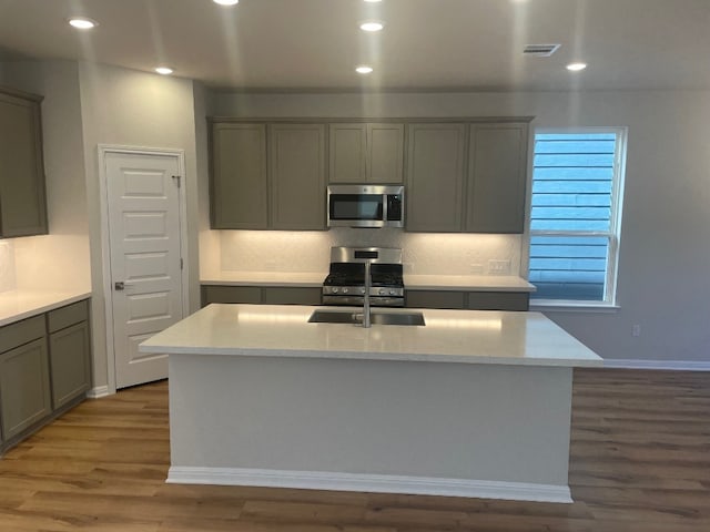 kitchen featuring a kitchen island with sink, dark hardwood / wood-style flooring, and appliances with stainless steel finishes