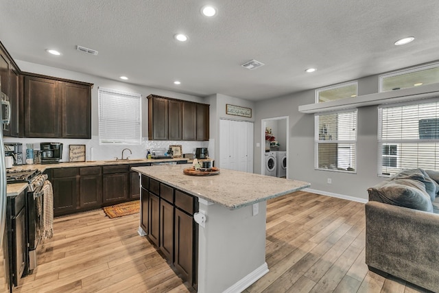 kitchen featuring a center island, separate washer and dryer, light hardwood / wood-style flooring, and stainless steel gas range