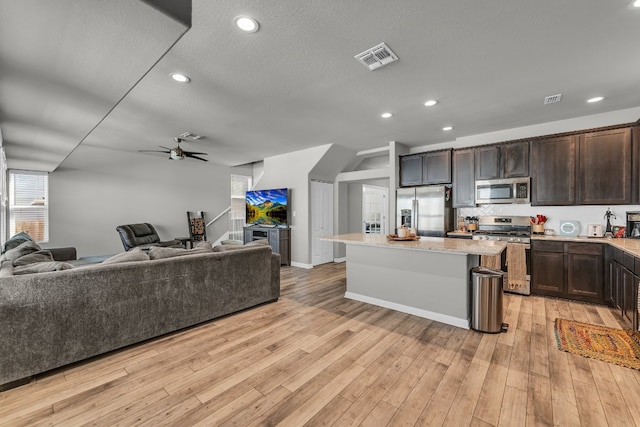 kitchen with ceiling fan, a center island, light wood-type flooring, and appliances with stainless steel finishes