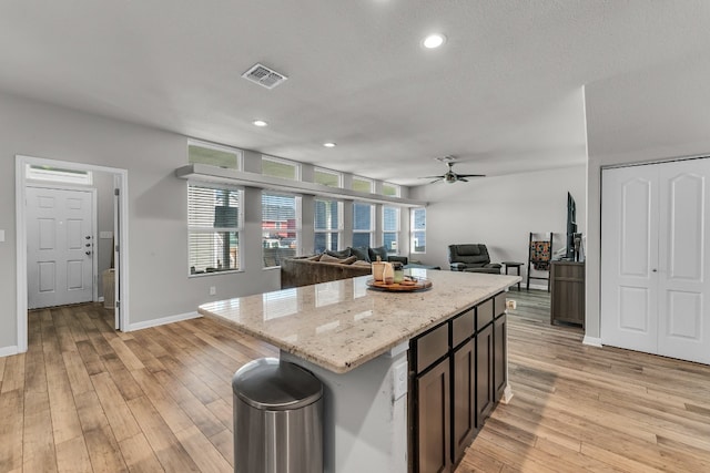 kitchen featuring ceiling fan, a center island, light hardwood / wood-style floors, and dark brown cabinets