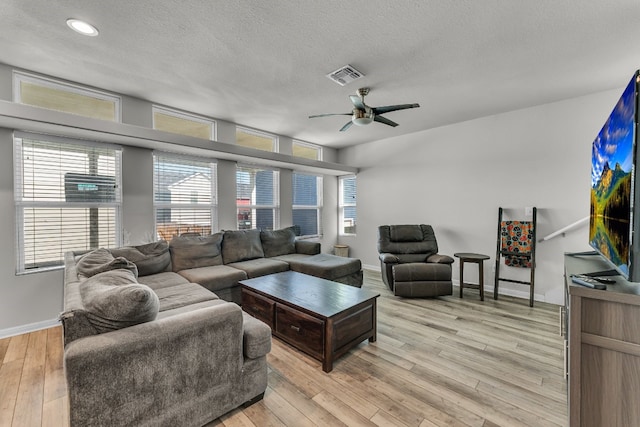 living room featuring ceiling fan, a textured ceiling, and light wood-type flooring