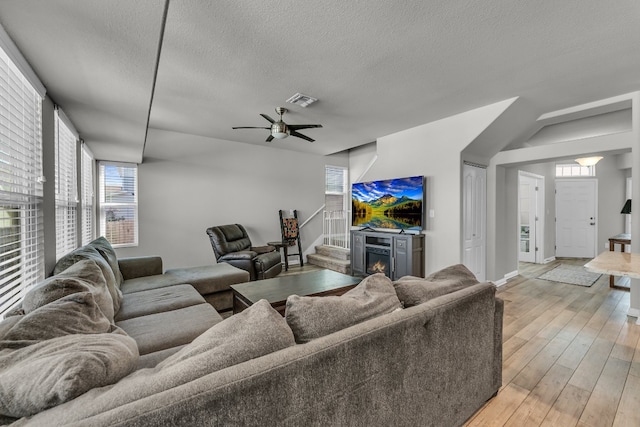 living room with a textured ceiling, light hardwood / wood-style floors, and ceiling fan