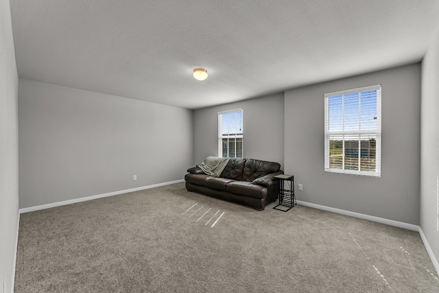 living area with a wealth of natural light, light colored carpet, and a textured ceiling