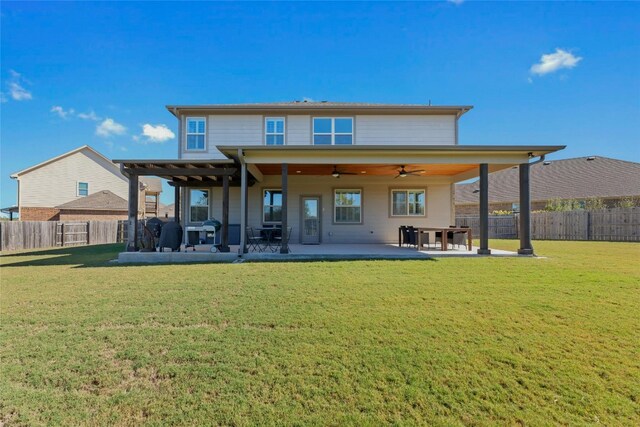 rear view of house with ceiling fan, a patio area, and a lawn