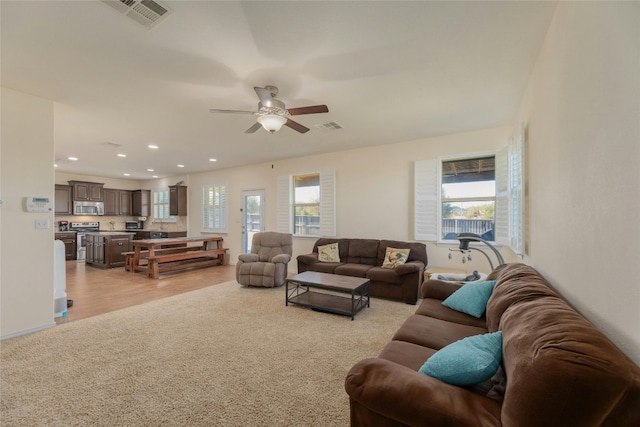 living room featuring a wealth of natural light, light colored carpet, and ceiling fan