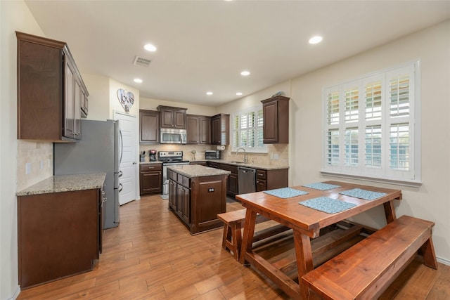 kitchen with stainless steel appliances, a kitchen island, dark brown cabinets, and sink