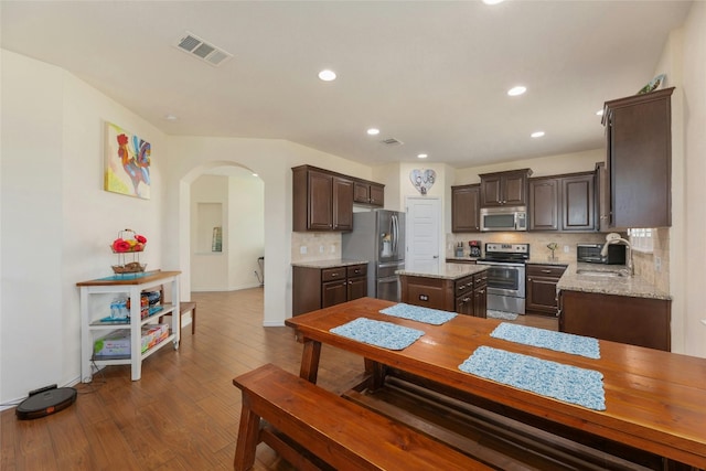 kitchen featuring a kitchen island, tasteful backsplash, sink, light stone counters, and stainless steel appliances