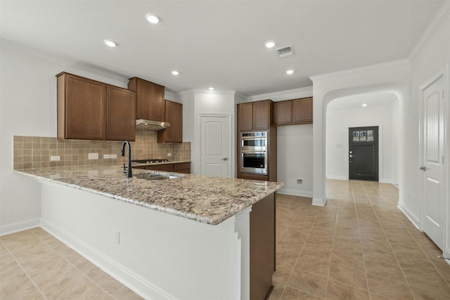 kitchen with sink, decorative backsplash, light stone countertops, double oven, and kitchen peninsula