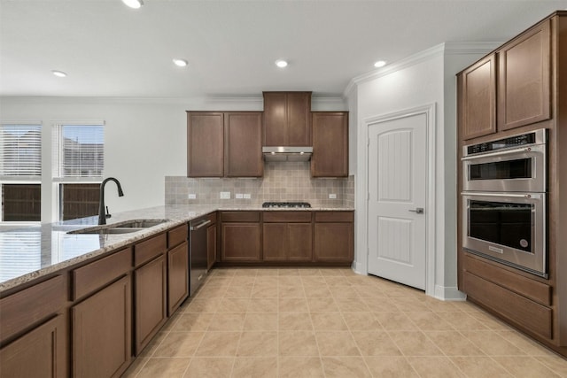 kitchen with backsplash, light stone counters, stainless steel appliances, crown molding, and sink