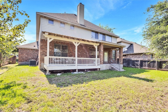 rear view of house featuring a lawn and central AC