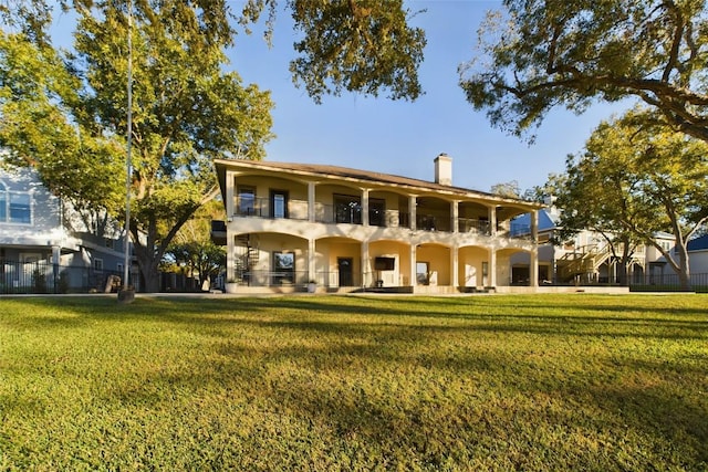 back of property featuring a balcony, a patio area, and a lawn