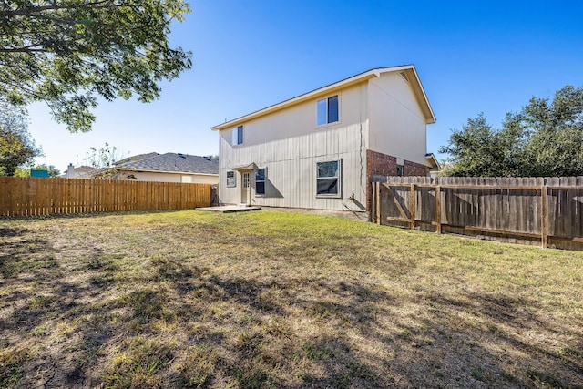 back of house with a lawn and a fenced backyard