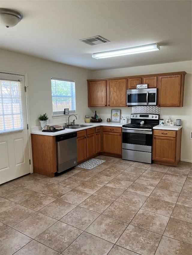 3104 Tyler Ln, Taylor, TX 76574 - kitchen featuring stainless steel appliances, brown cabinetry, a sink, and light countertops