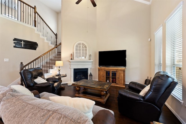 living room with hardwood / wood-style flooring, ceiling fan, and a high ceiling