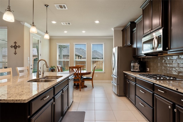 kitchen with decorative light fixtures, sink, stainless steel appliances, and an island with sink