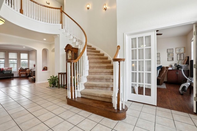 staircase with crown molding, tile patterned flooring, and a high ceiling