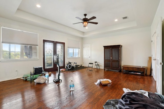 workout room with dark hardwood / wood-style flooring, plenty of natural light, a raised ceiling, and french doors