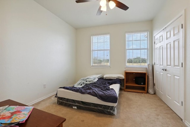 carpeted bedroom featuring ceiling fan and a closet