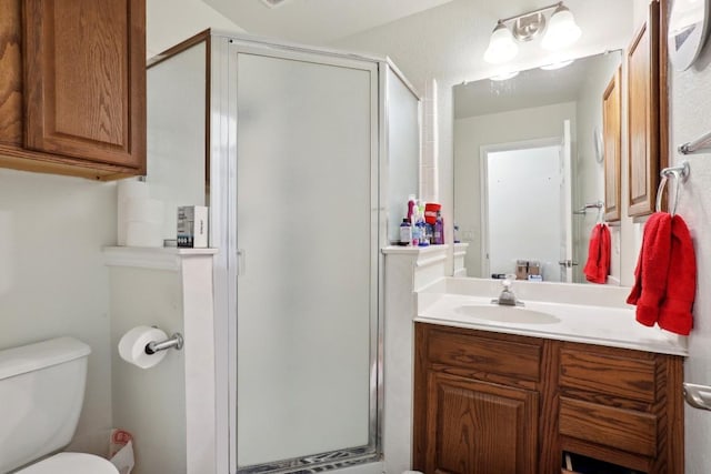 bathroom featuring vanity, toilet, and a shower with shower door