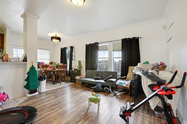 living room with crown molding, wood-type flooring, decorative columns, and a healthy amount of sunlight