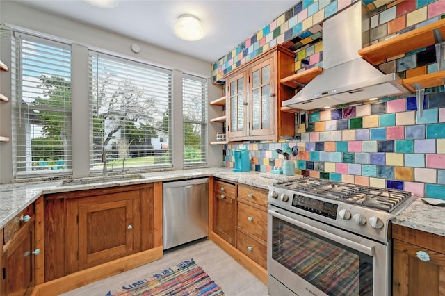 kitchen featuring appliances with stainless steel finishes, island exhaust hood, a sink, and light stone countertops