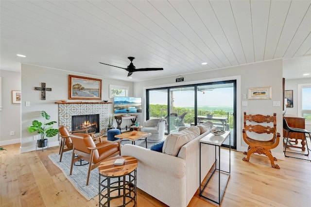 living room featuring ceiling fan, recessed lighting, baseboards, light wood-style floors, and a tiled fireplace