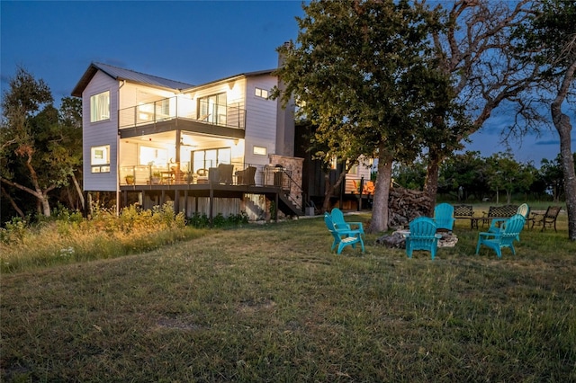 back of house featuring metal roof, a balcony, a fire pit, stairs, and a wooden deck