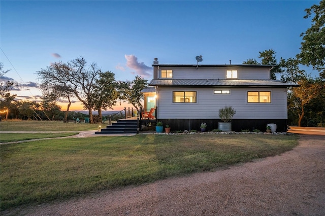 back of property at dusk with metal roof and a yard