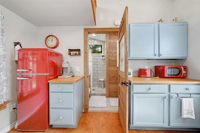 kitchen with light wood-style flooring, light countertops, and freestanding refrigerator