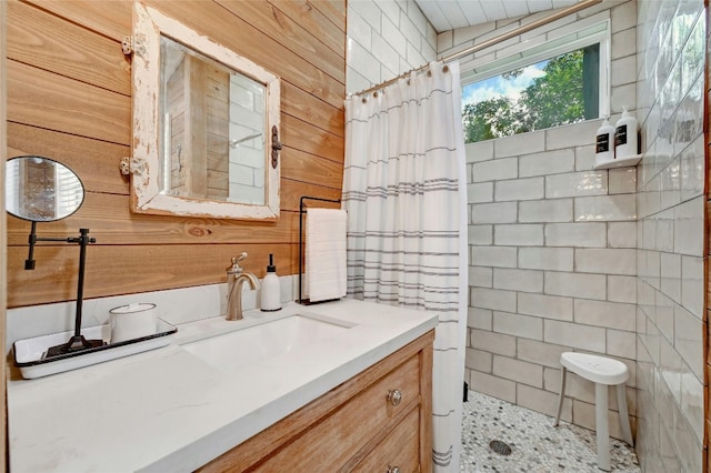 full bath featuring tiled shower, vanity, and wooden walls