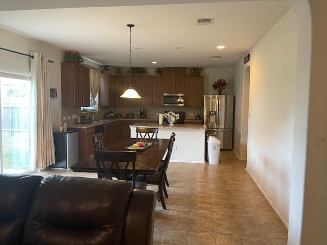 kitchen featuring a center island, sink, hanging light fixtures, stainless steel appliances, and tasteful backsplash