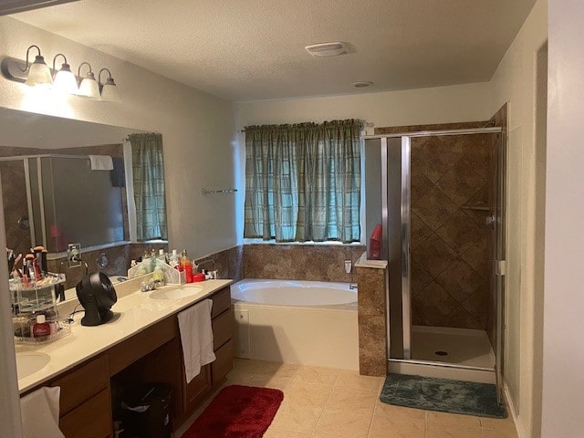 bathroom with plus walk in shower, tile patterned flooring, vanity, and a textured ceiling